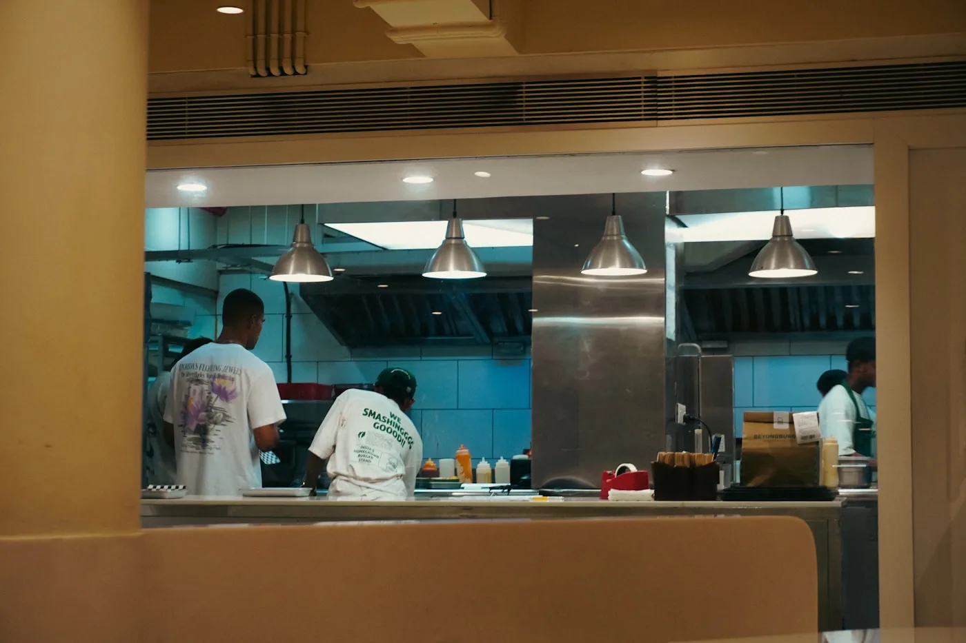 Several employees coordinating orders at the service window of a commercial kitchen