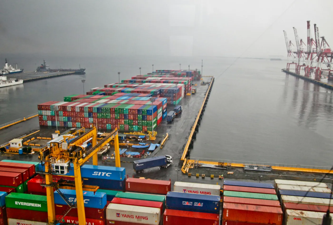 Stacks of shipping containers in a waterfront terminal yard